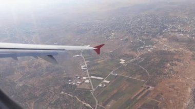 Uçak uçuşu. İnişe geçiyorum. Gün batımında uçağın penceresinden güzel gökyüzüne, bulutlara ve karaya bak.