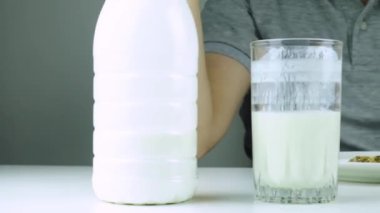 Kahvaltıda süt, kefir ve beyaz arka planda sağlıklı tahıllı kurabiye yiyen bir adam. Genç adam sağlıklı yemek yiyor.. 