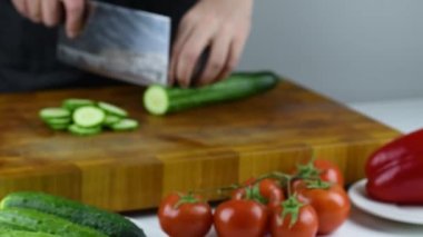 Şef 'in elleri Japon bıçağıyla geleneksel Asya mutfağı için sebze doğruyor. Profesyonel suşi şefi salatalık kesiyor..