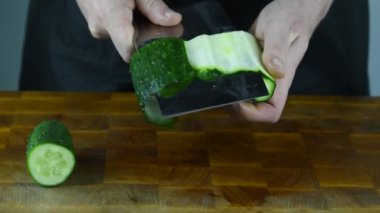 Şef 'in elleri Japon bıçağıyla geleneksel Asya mutfağı için sebze doğruyor. Profesyonel suşi şefi salatalık kesiyor..