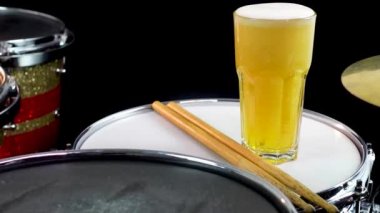 Profesyonel bateri setinde bir bardak light bira. Davullar, davullar ve ziller, canlı müzik rock konserinde, kulüp sahnesinde, barda ya da kayıt stüdyosunda. Siyah arkaplan.