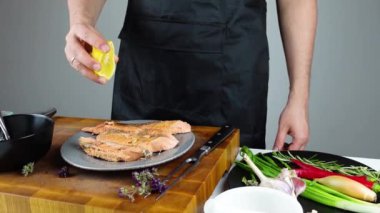 Şef aşçı tuzlu kabukta pişirilmiş balığa limon sıkar. Deniz ürünleri pişirme. Tuz kabuğunun altında sebzeli somon veya deniz kabuğu..