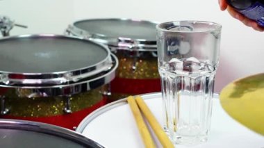 Profesyonel bateri setinde bir bardak light bira. Davullar, davullar ve ziller, canlı müzik rock konserinde, kulüp sahnesinde, barda ya da kayıt stüdyosunda. Siyah arkaplan.
