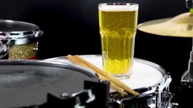 Profesyonel bateri setinde bir bardak light bira. Davullar, davullar ve ziller, canlı müzik rock konserinde, kulüp sahnesinde, barda ya da kayıt stüdyosunda. Siyah arkaplan.