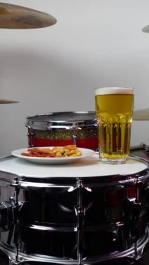 Profesyonel bateri setinde bir bardak light bira. Davullar, davullar ve ziller, canlı müzik rock konserinde, kulüp sahnesinde, barda ya da kayıt stüdyosunda. Siyah arkaplan.