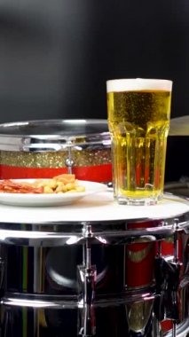 Profesyonel bateri setinde bir bardak light bira. Davullar, davullar ve ziller, canlı müzik rock konserinde, kulüp sahnesinde, barda ya da kayıt stüdyosunda. Siyah arkaplan.