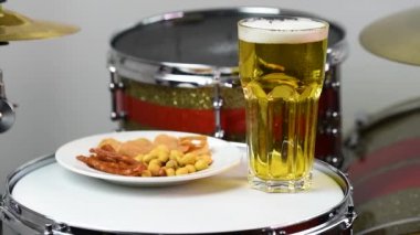Profesyonel bateri setinde bir bardak light bira. Davullar, davullar ve ziller, canlı müzik rock konserinde, kulüp sahnesinde, barda ya da kayıt stüdyosunda. Beyaz arkaplan.
