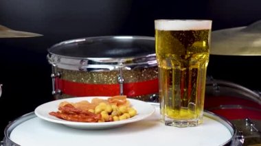 Profesyonel bateri setinde bir bardak light bira. Davullar, davullar ve ziller, canlı müzik rock konserinde, kulüp sahnesinde, barda ya da kayıt stüdyosunda. Siyah arkaplan.