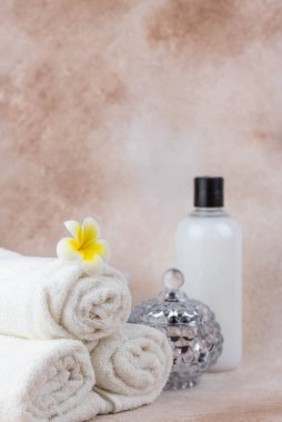 Sağlık merkezindeki masaj masasında spa natürmort bezi. Bej arka planda aromatik mumlarla kıvrılmış sıcak havlu. Aroma terapi seti. Uyum kavramı, denge ve meditasyon, rahatla, güzellik.