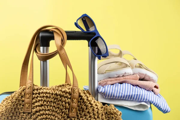 Blauer Koffer Mit Sonnenbrille Sommerkleidung Schuhen Und Korbtasche Auf Gelbem — Stockfoto