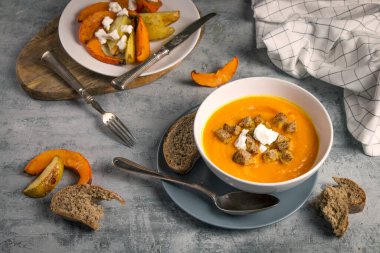 Taze Hokkaido Balkabağı Kremalı Çorbası 'nı kapatıyoruz. Ekmek parçaları, fırınlanmış pompa iğnesi, patates ve kırsal alanda keçi peyniri ile birlikte.