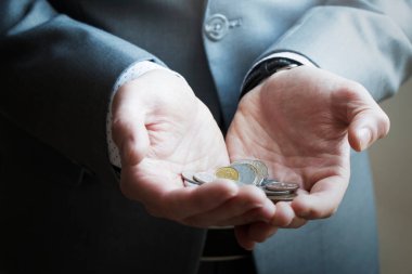 Çeşitli madeni paralar tutan bir işadamının ellerini kapatın.