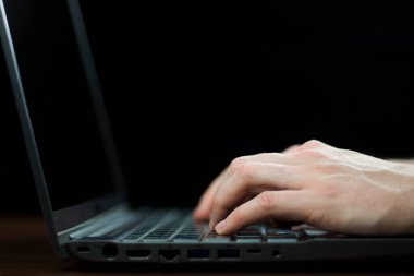 Klavyede yazı yazan bir adamın ellerini koyu arkaplanda kapat.