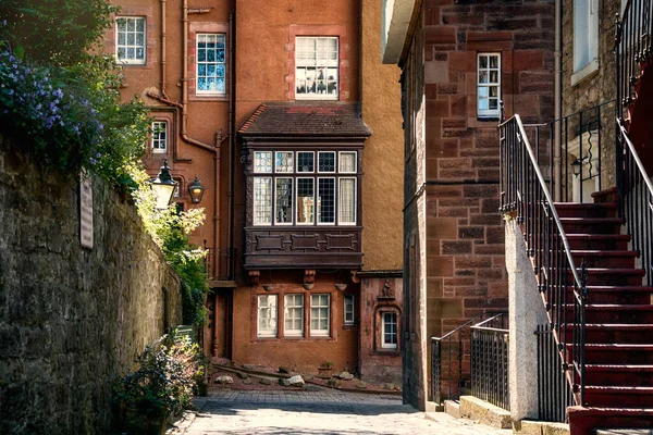 Edinburgh 'da tarihi küçük evleri, merdivenleri ve lambaları olan dar bir caddenin fotoğrafı.