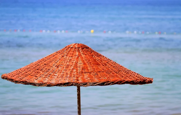 Halm paraply på en strand — Stockfoto