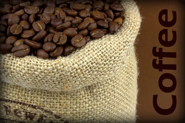 Grains de café dans un sac de lin sur fond brun et texte échantillon — Photo