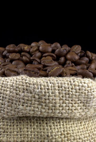 Koffie bonen in een linnen zak op zwarte achtergrond — Stockfoto