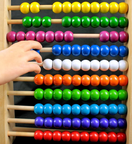 Abacus with many colorful beads and child's hand — Stock Photo, Image