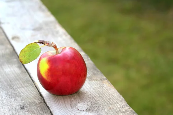 Röd, fräsch och ekologisk äpple på gamla tabellen Royaltyfria Stockfoton
