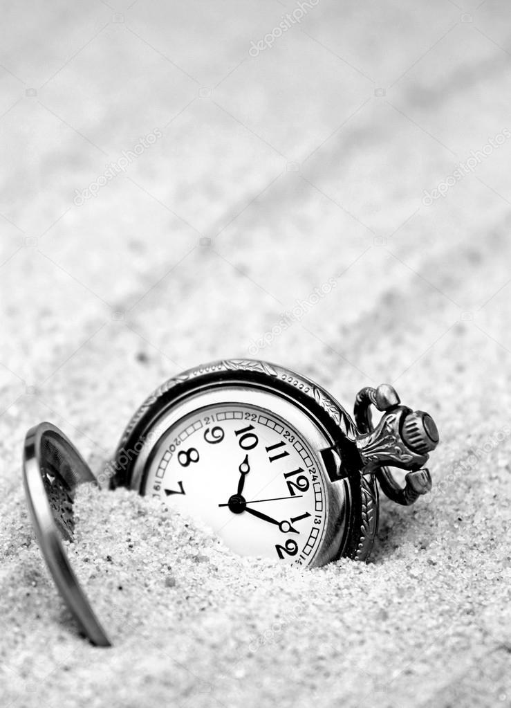 Antique pocket watch buried in sand. B&W image