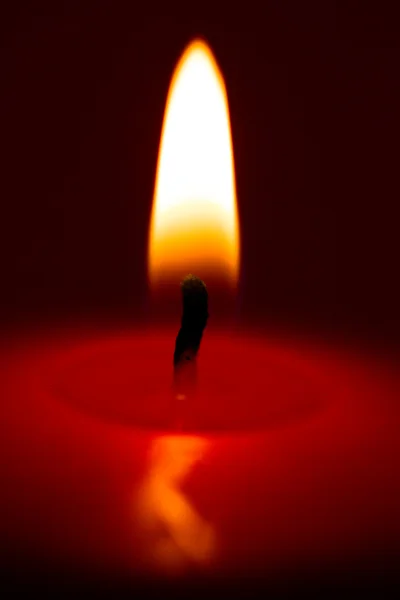 Primo piano di una candela in fiamme su uno sfondo scuro — Foto Stock