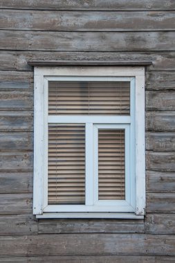 Plastik pencere içeriden kapalı, ahşap bir köy evinin perdeleri var.