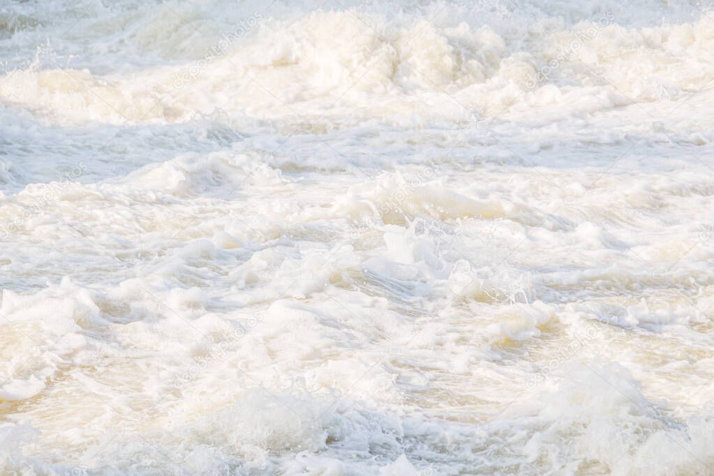 Stormy waters of the river with foam and flying splashes and drops of water