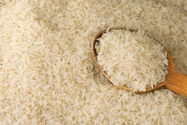 Uncooked rice and wood spoon — Stock Photo, Image