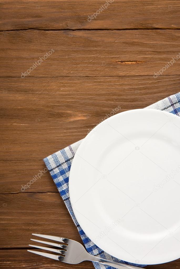 white plate and fork on wood