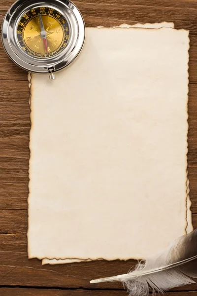 Ink feather and compass on parchment background — Stock Photo, Image