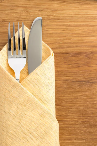 Knife and fork at napkin on wood — Stock Photo, Image