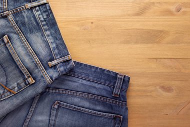 Ahşap masada kot pantolonun cebinde. Ahşap arkaplan dokusunda kot pantolon yığını
