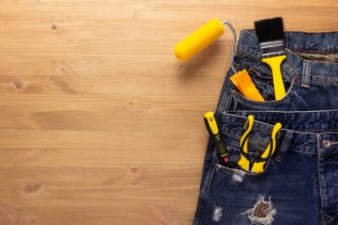 Ahşap masa arkasında kot pantolon cebinde alet çantası. Ev yenileme konsepti