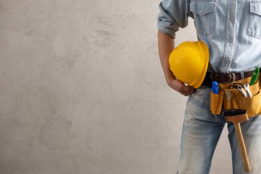 İnşaat miğferi tutan işçi beton ya da beton duvarın yanında. Ev dekorasyonu için erkek eli ve sert şapka. Ev yenileme konsepti