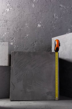 Soyut arkaplan dokusunda tuğlada beton küp ve mezura ölçüsü. Sanat veya inşaat konsepti