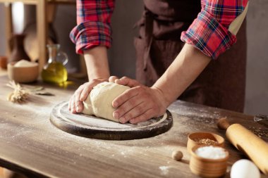 Fırıncı adam masada ev yapımı ekmek pişirmek için hamur ve fırın malzemeleri yapıyor. Fırın konsepti ve erkek eli