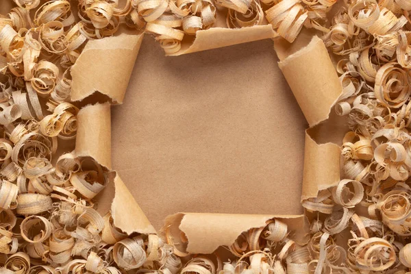 Wood shavings on torn paper background. Wooden shaving at cardboard texture