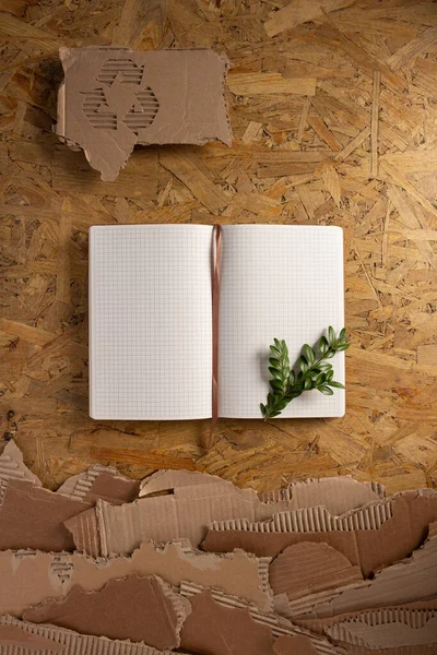 Notebook and cardboard torn waste paper at chipboard background texture. Recycling concept and brown cardboard pieces