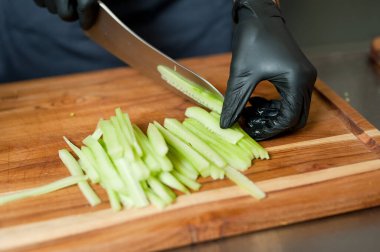 The cook cuts vegetables with a knife to prepare the dish. Cutting vegetables.