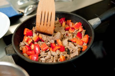 Cook fries meat in a pan with vegetables.
