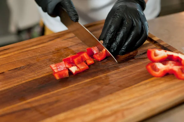 The cook cuts vegetables with a knife to prepare the dish. Cutting vegetables.