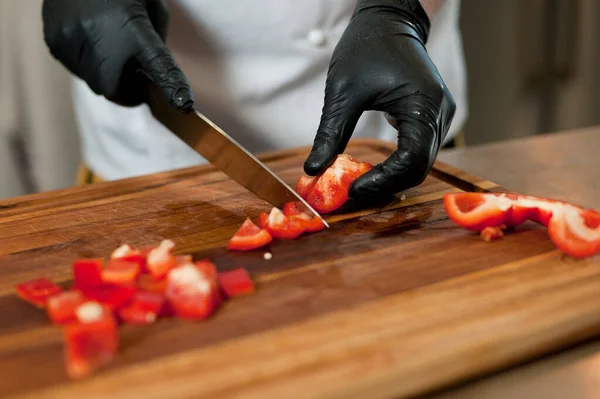 The cook cuts vegetables with a knife to prepare the dish. Cutting vegetables.