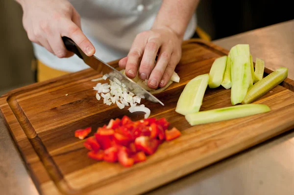 The cook cuts vegetables with a knife to prepare the dish. Cutting vegetables.