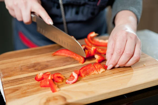 The cook cuts vegetables with a knife to prepare the dish. Cutting vegetables.