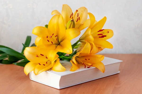 Bouquet of orange lilies on a book, a gift on the occasion of a solemn event