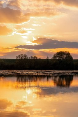 Nehirde gün doğumu ya da gün batımı. Gökyüzünün yansıması ve nehir suyundaki bulutlar.