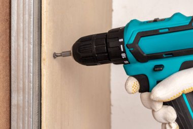 Usta metal profile alçıpan takmak için elektrikli tornavida kullanıyor.