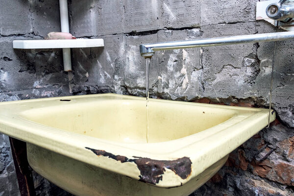 An old washbasin in a shabby place in a poor quarter. Kitchen under repair