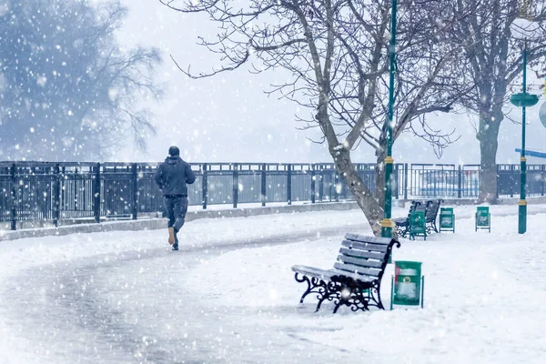 A man takes a morning jog in a park in the city of Khmelnytskyi, Ukraine, during a snowfall