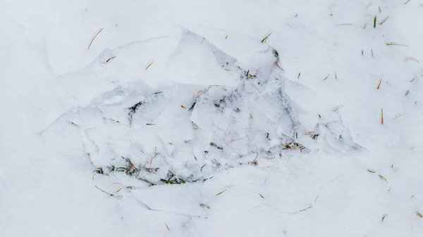 The imprint of a human foot on the ice-covered snow